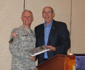 Col. Mike Flanagan, USA (l), program manager for training devices, Program Executive Office for Simulation, Training and Instrumentation, receives a speaker's TechNet portfolio from Fred Eisele, chapter vice president for programs, at the October meeting.